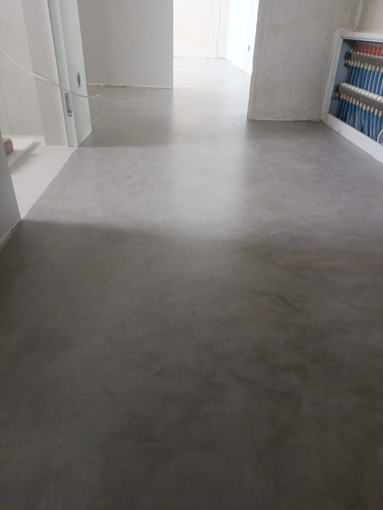 Contemporary living room with Silk Plaster microcement floor and dark accent wall